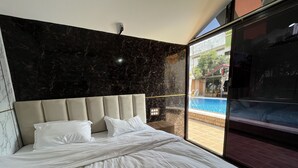 Un dormitorio con una cama grande, cabecera de mármol y vistas a una piscina exterior.