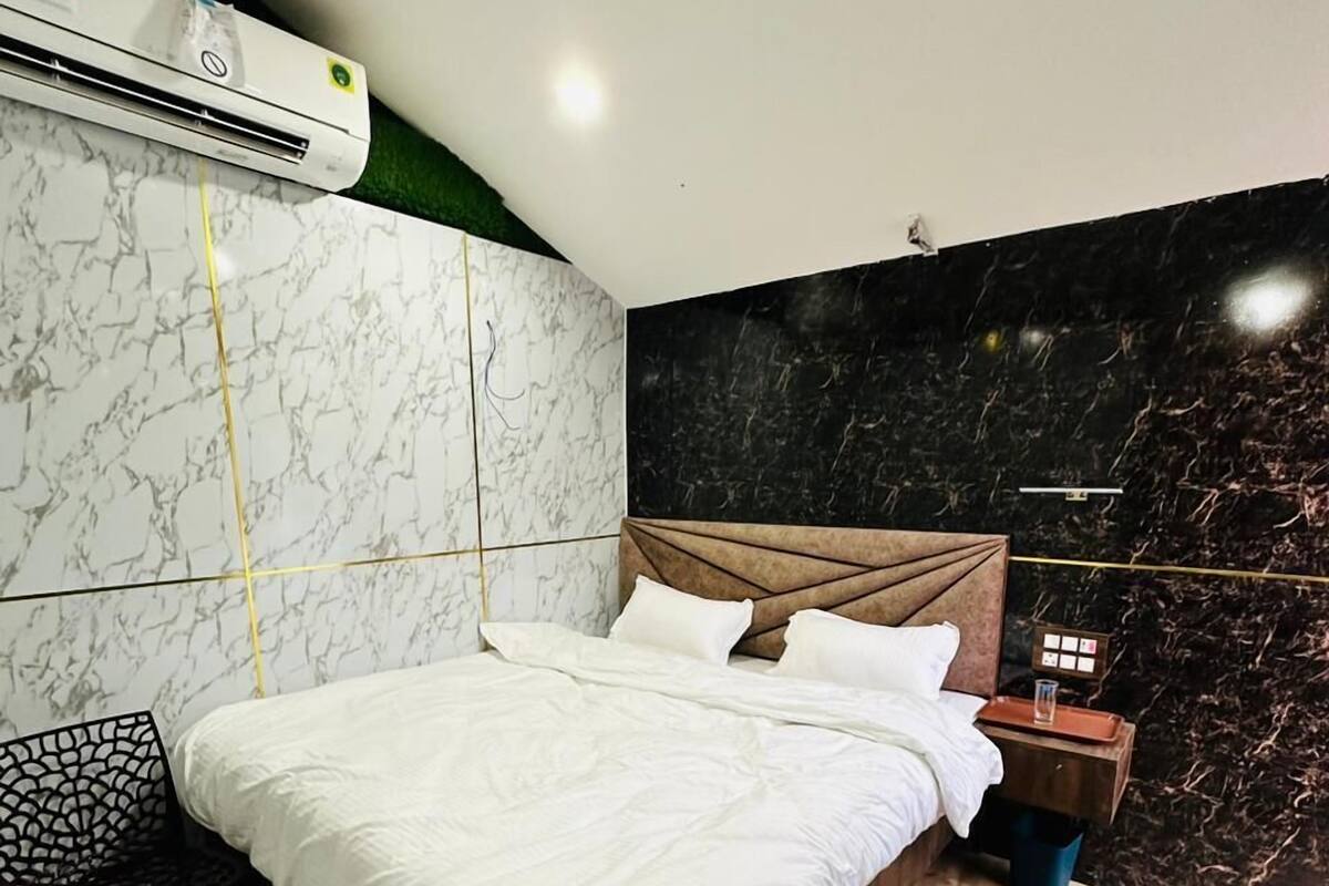 Quarto com cama, cadeira, mesa de cabeceira e ar-condicionado fixado na parede.