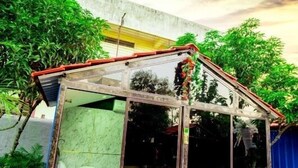 Una pequeña estructura cerrada con puerta de cristal y techo, rodeada de follaje.