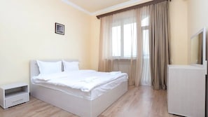 A bedroom with a bed, a nightstand, a dresser, and a window with curtains. - Stay Inn on Argishti 11 (Yerevan)