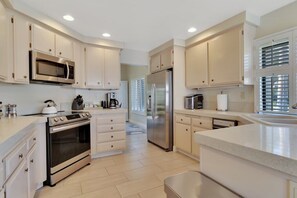 A modern kitchen with stainless steel appliances, white cabinetry, and a large island.