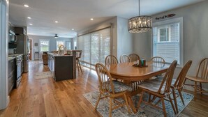 Une cuisine spacieuse avec un plancher en bois, un coin repas avec une table ronde et des chaises, et un grand îlot central.