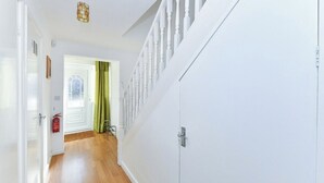 En hall med en vit dörr, en brandsläckare och en grön gardin.