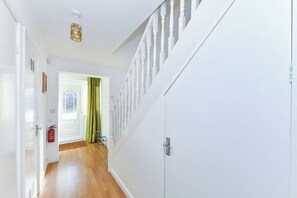 En hall med en vit dörr, en brandsläckare och en grön gardin.