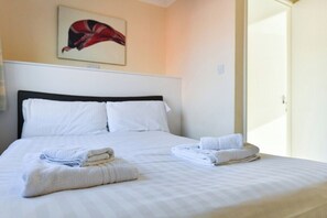 A hotel room with a bed, pillows, and folded towels.