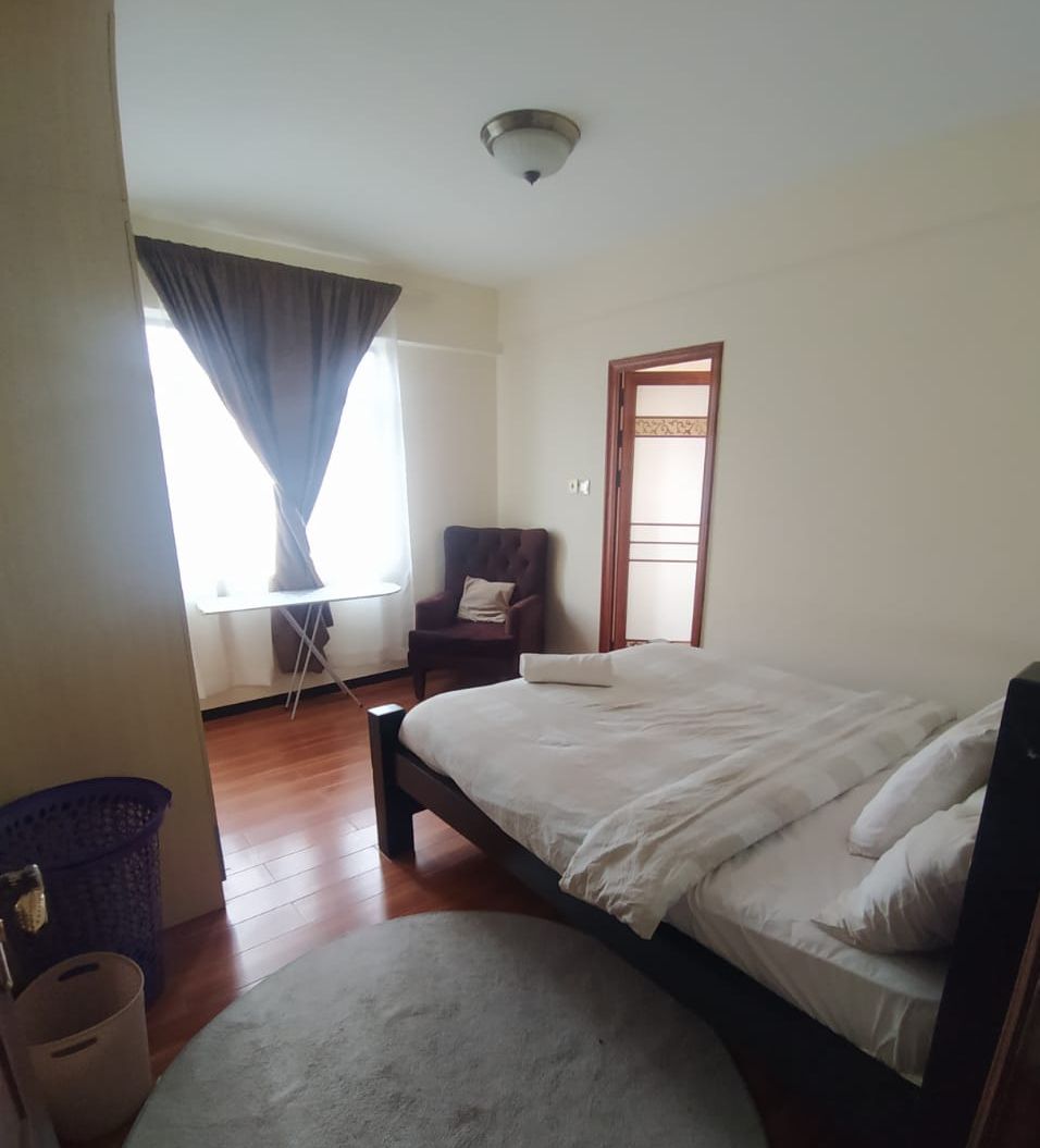A bedroom with a bed, a chair, a window with curtains, and a door.
