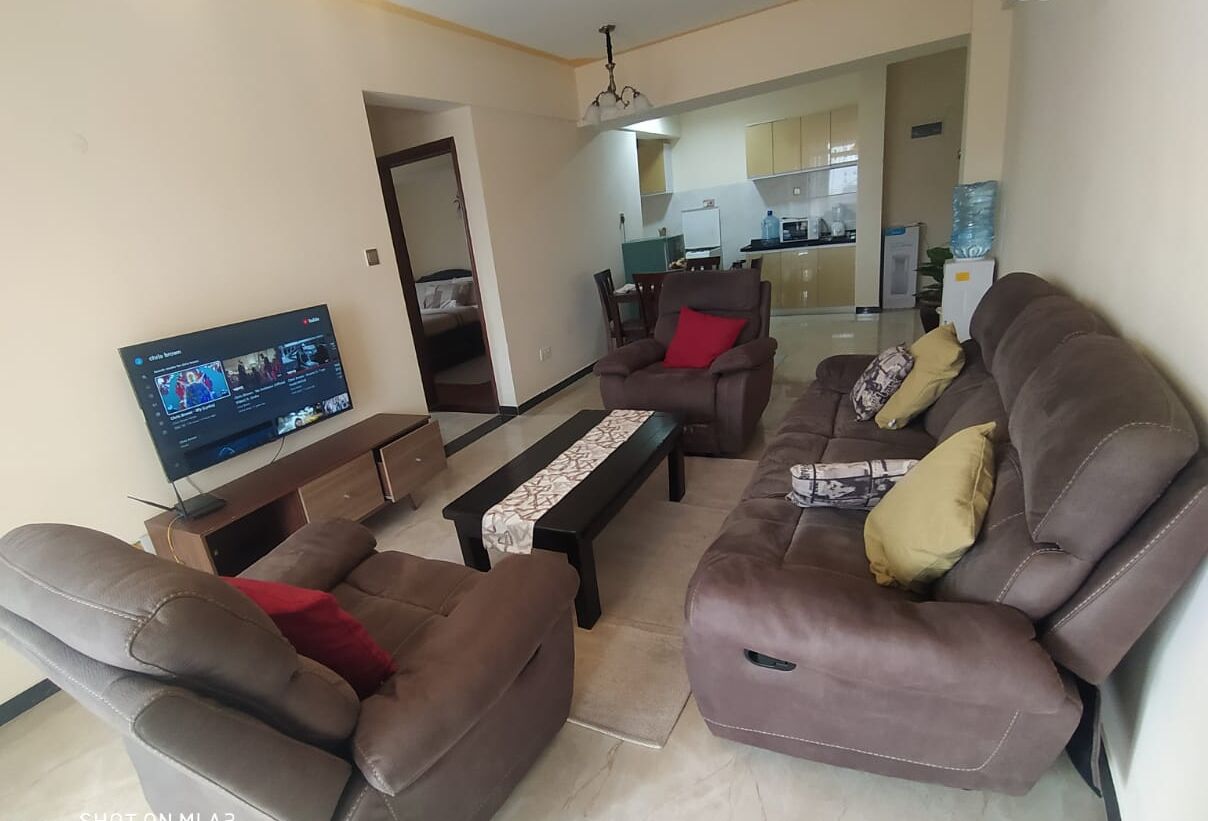 A living room with a sofa set, a coffee table, and a flat-screen TV.