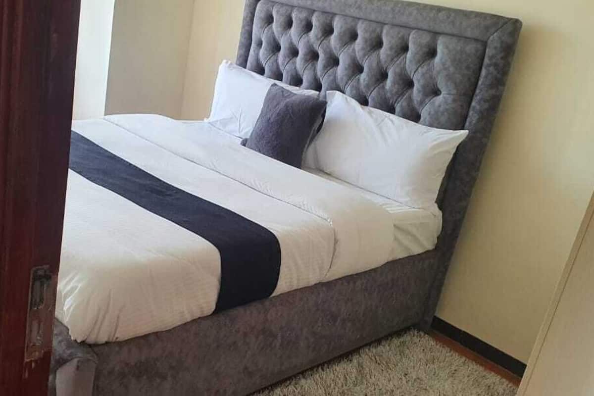 A bed with a tufted headboard, white bedding, and a dark accent.