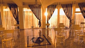 Amplia habitación con piso de mármol pulido, varias sillas dispuestas alrededor de un área central y grandes ventanales con cortinas a rayas.