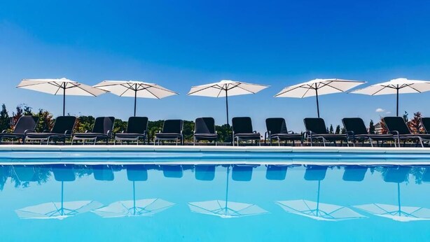 Una piscina con sillas de descanso y sombrillas.