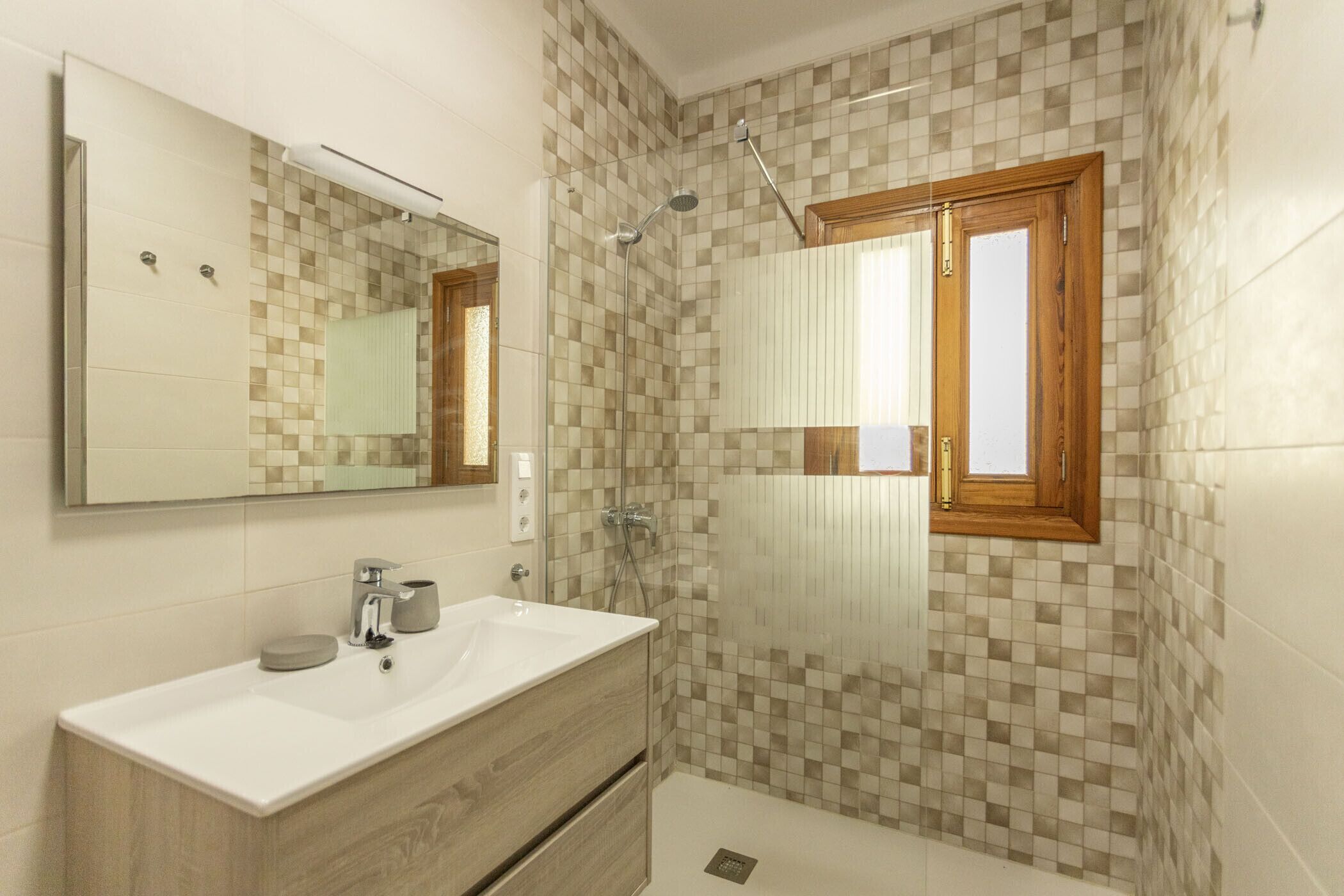 Un bagno moderno con uno specchio grande, un lavandino e una doccia.
