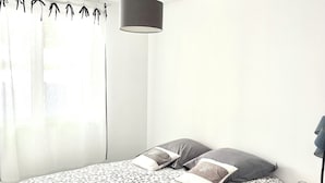 A modern bedroom with a bed, a bedside table, a lamp, and a window with curtains.