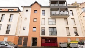 A multi-story residential building with a red garage door, a brick facade, and a modern balcony structure. - L'air du Large by Interhome (Saint Malo)