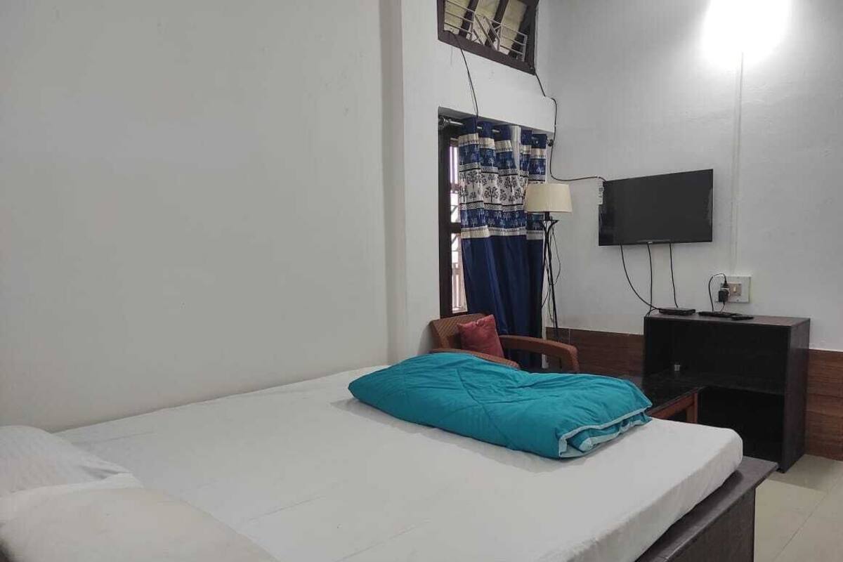 A bedroom with a bed, a chair, a TV, and a desk.
