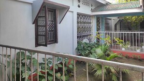 Ein Gebäude mit weißer Fassade, einem Balkon mit Metallgeländer und einem überdachten Bereich mit grüner Dachbegrünung.