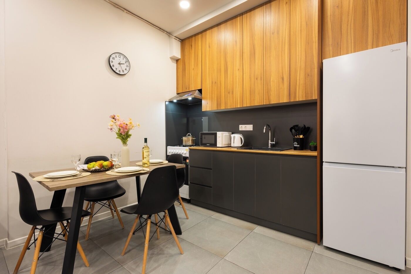 Una cocina moderna con una mesa de comedor, sillas, un reloj y un refrigerador.