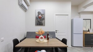 Une cuisine moderne avec une table à manger, des chaises, un réfrigérateur et un tableau accroché au mur.