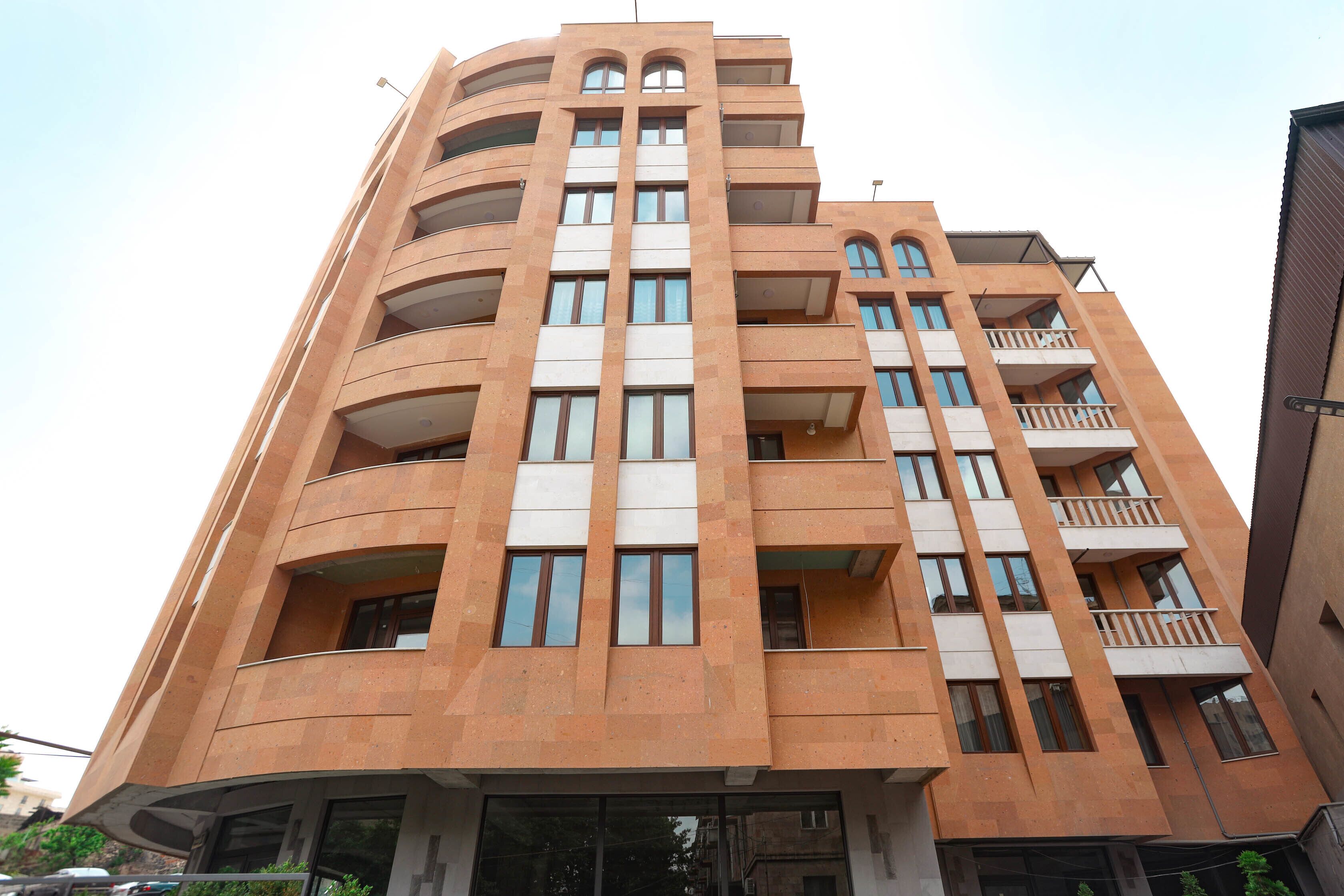A multi-story building with a modern architectural design, featuring balconies and large windows.