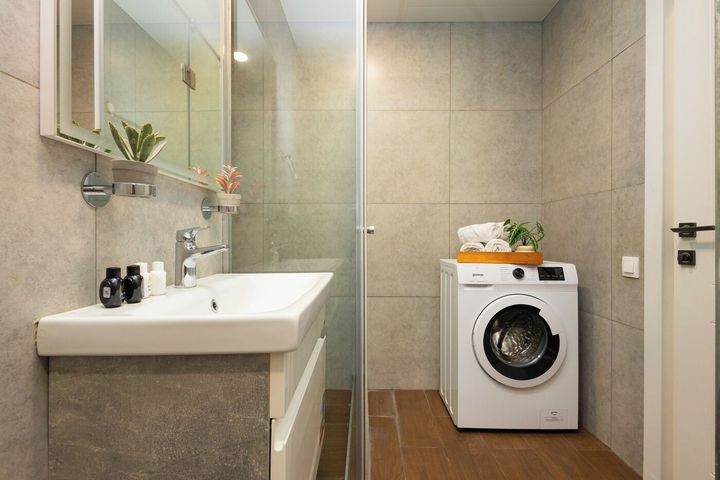 Une petite salle de bain comprenant un lavabo, un miroir et un lave-linge.