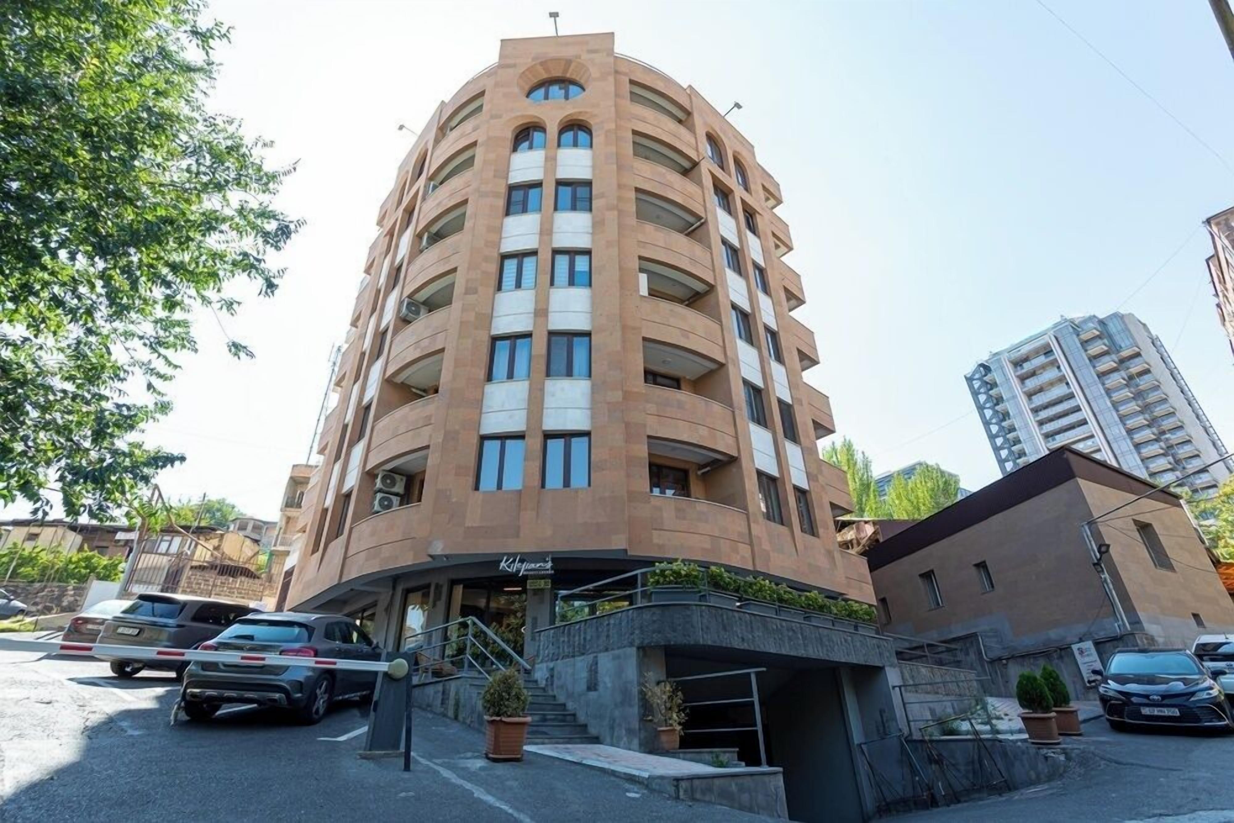 Un hôtel à plusieurs étages, doté d’une façade incurvée, d’un parking extérieur et d’un petit hall d’entrée avec des marches.
