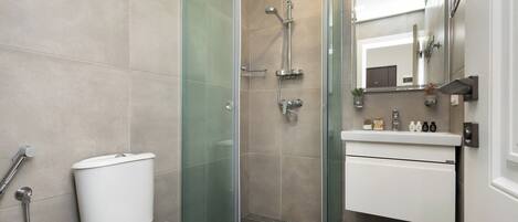 Un bagno moderno con doccia vetrata, un WC bianco e un mobile lavabo con specchio.