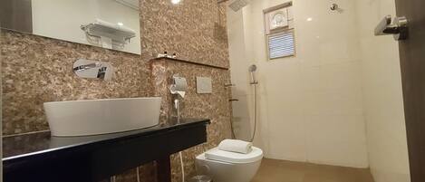 A modern bathroom with a marble sink, a toilet, and a shower.