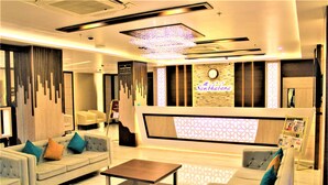 Een moderne hotel lobby met een zithoek, een salontafel en een receptiebalie.