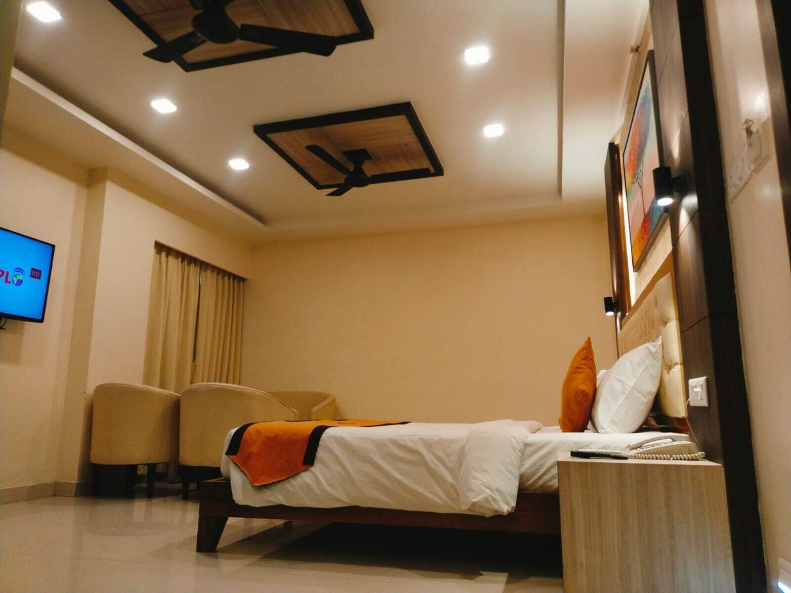 A hotel room with a bed, a desk, a chair, a TV, and a ceiling fan.