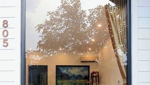 A bedroom with a large window, a bed, a painting, and a nightstand. - Vivian riverside cottage - Ninh Bình (Ninh Binh)