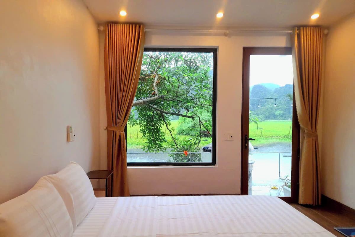 Un dormitorio con una cama grande, una ventana con cortinas y vistas a zonas verdes.