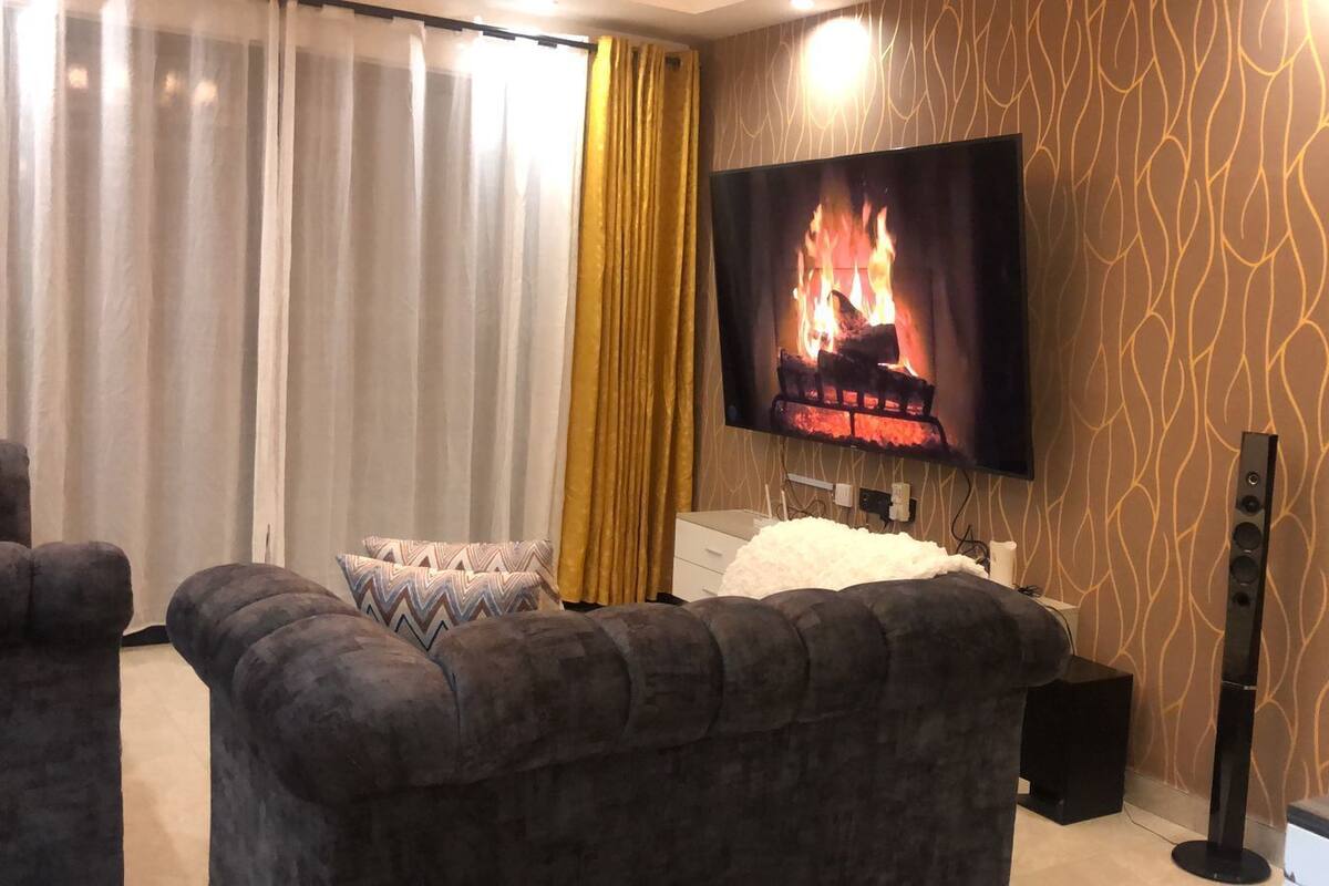 Ein modernes Wohnzimmer mit Kamin, Flachbildfernseher und bequemen Sitzmöglichkeiten.