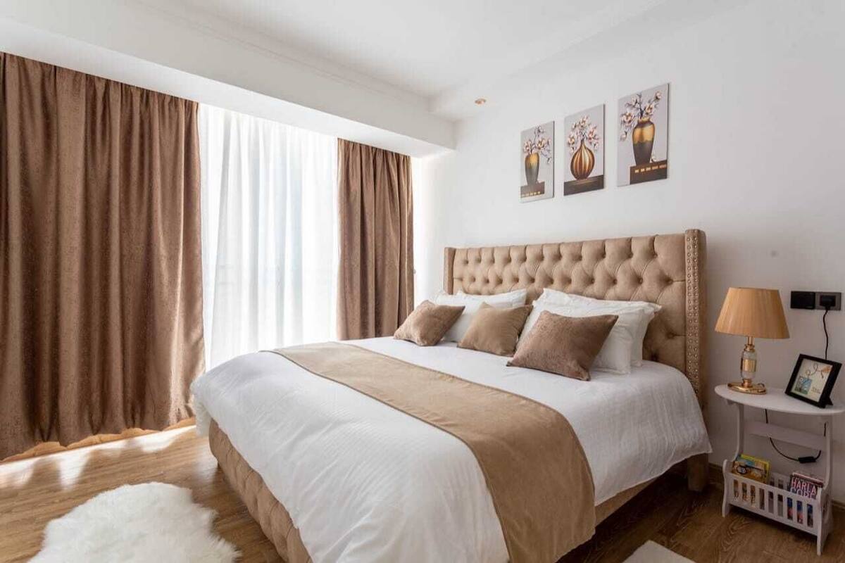 Ein Schlafzimmer mit einem großen Bett, einer weißen Wand und einem Fenster mit Vorhängen.