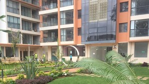 A modern building with multiple balconies and a well-maintained garden area with various plants and a lawn. - Lux Suites Urban Oasis Apartments (Nairobi)