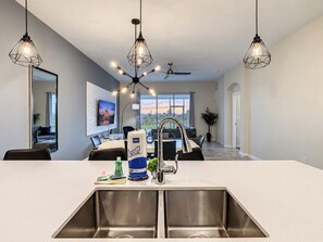 A modern kitchen with a large island, stainless steel appliances, and pendant lighting. - Cozy Hideaway/Waterpark/GameRoom (Davenport)
