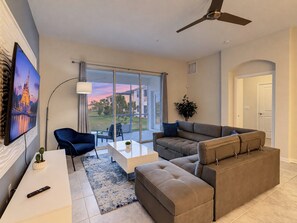 A modern living room with a sofa, a coffee table, and a TV mounted on the wall.