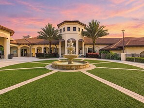 A courtyard with a central fountain, surrounded by well-maintained grass and a building with a tiled roof. - Cozy Hideaway/Waterpark/GameRoom (Davenport)