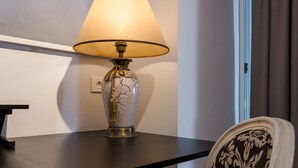 A table lamp with a cracked glass base and a beige lampshade on a dark table.