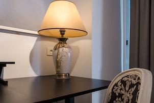 Una lampada da tavolo con un paralume color crema su un tavolo scuro, e un basamento in vetro crepato.