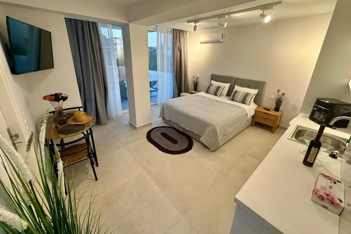 Um quarto moderno com uma cama, mesas de cabeceira, uma escrivaninha e uma televisão.