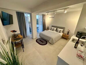 A modern bedroom with a bed, bedside tables, a desk, and a TV.