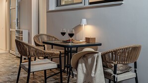 A dining area with wicker chairs, a table, two glasses of red wine, and a lamp.