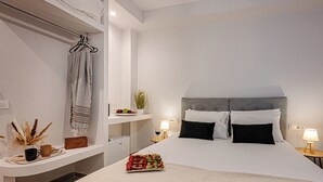 A modern hotel room with a large bed, bedside tables, a small desk, and a hanging towel rack.
