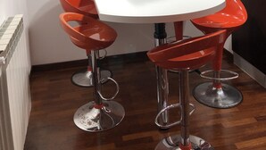 A compact kitchen with a white table, red bar stools, and a hanging light fixture. - Vacation Home Paradise (Viterbo)