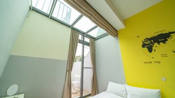 Un dormitorio con cama, una ventana con cortinas, un mapa en la pared y una mesita con espejo.
