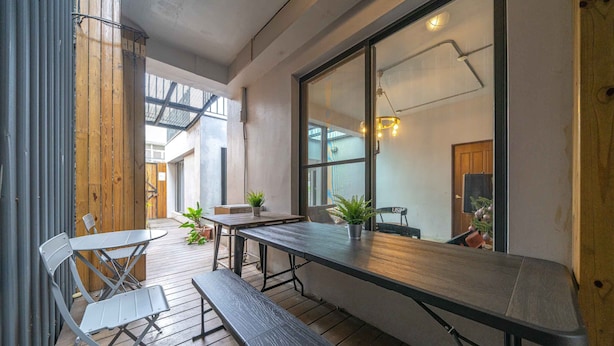 An outdoor patio with a wooden table and metal chairs, a bench, and potted plants. - B&B near the seaside (Ji'an)