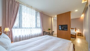 A hotel room with a large bed, a desk, a chair, a TV mounted on the wall, and a small bedside table. - B&B near the seaside (Ji'an)
