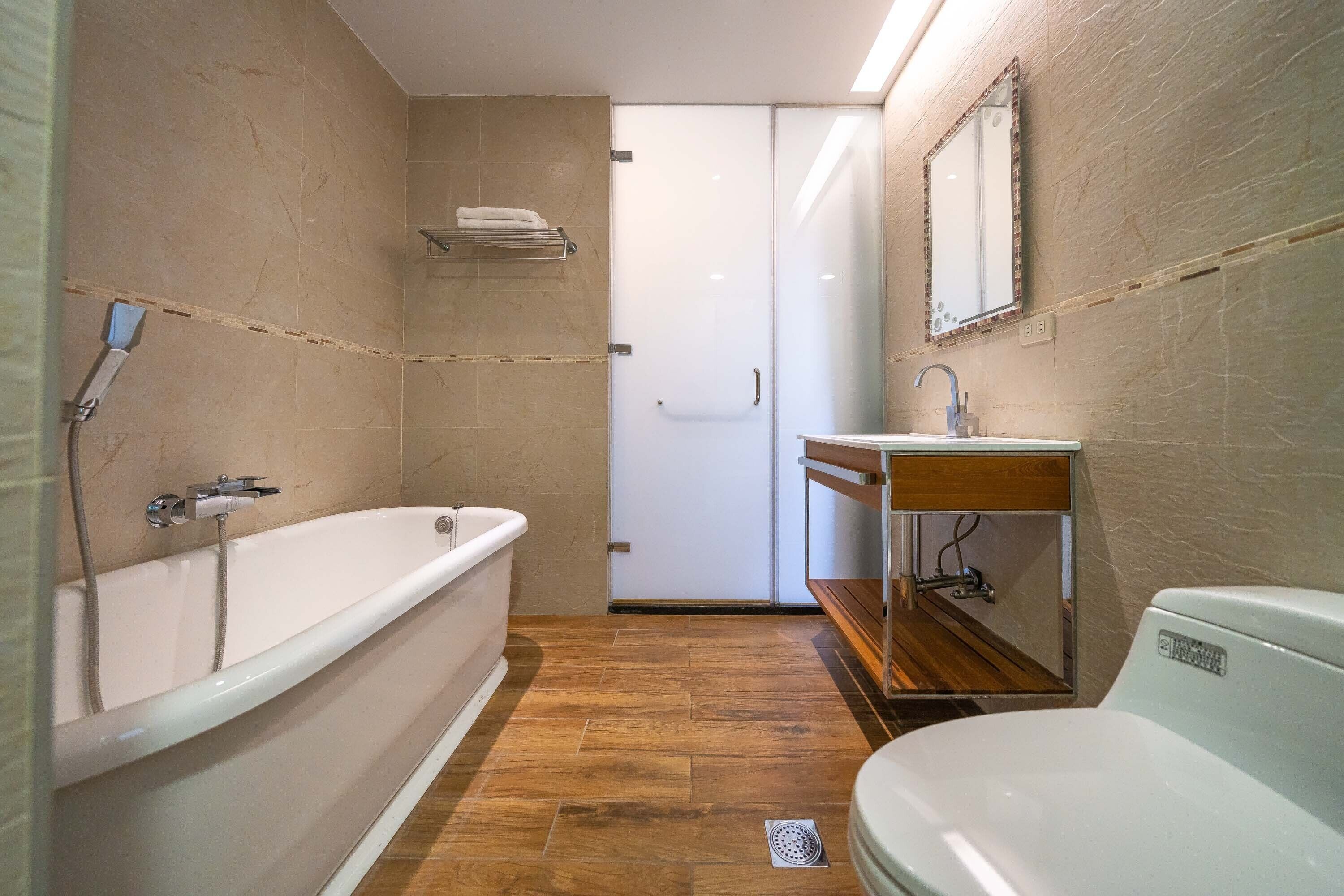 Ein modernes Badezimmer mit freistehender Badewanne, Waschbecken mit Spiegel und Toilette.