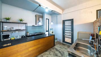 Uma cozinha compacta com ilha de madeira, pia de aço inoxidável e iluminação pendente.