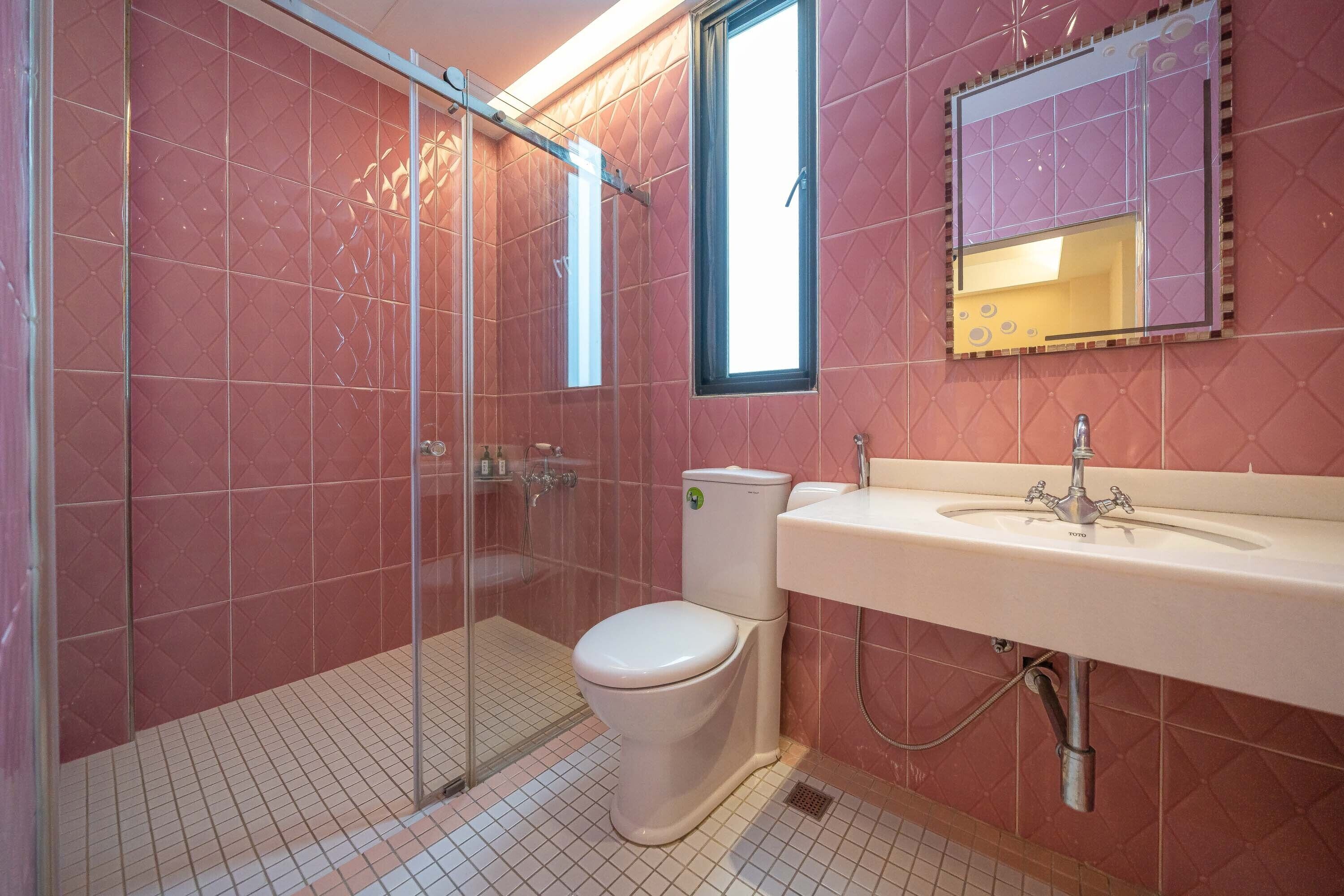 A bathroom with a glass-enclosed shower, a white toilet, and a sink with a mirror above it.