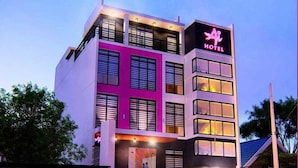 A modern hotel with a pink facade, multiple floors, and a staircase leading to the entrance. - OYO 1030 AI Hotel (Caloocan)